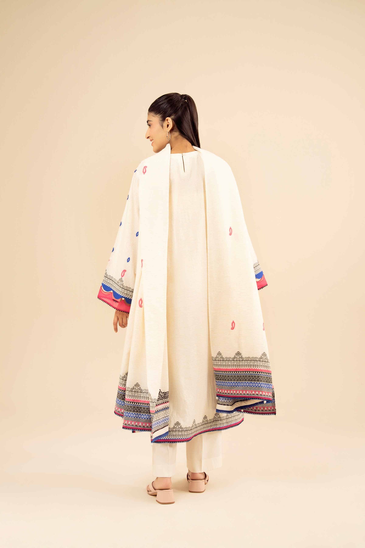 Back view of white printed suit with pink motifs and a white dupatta with blue and pink borders